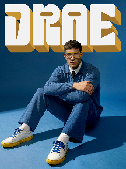 Drae campaign cover: model in a blue knit polo and tie wearing Blynq Drae oversized navigator glasses in Dune Main image