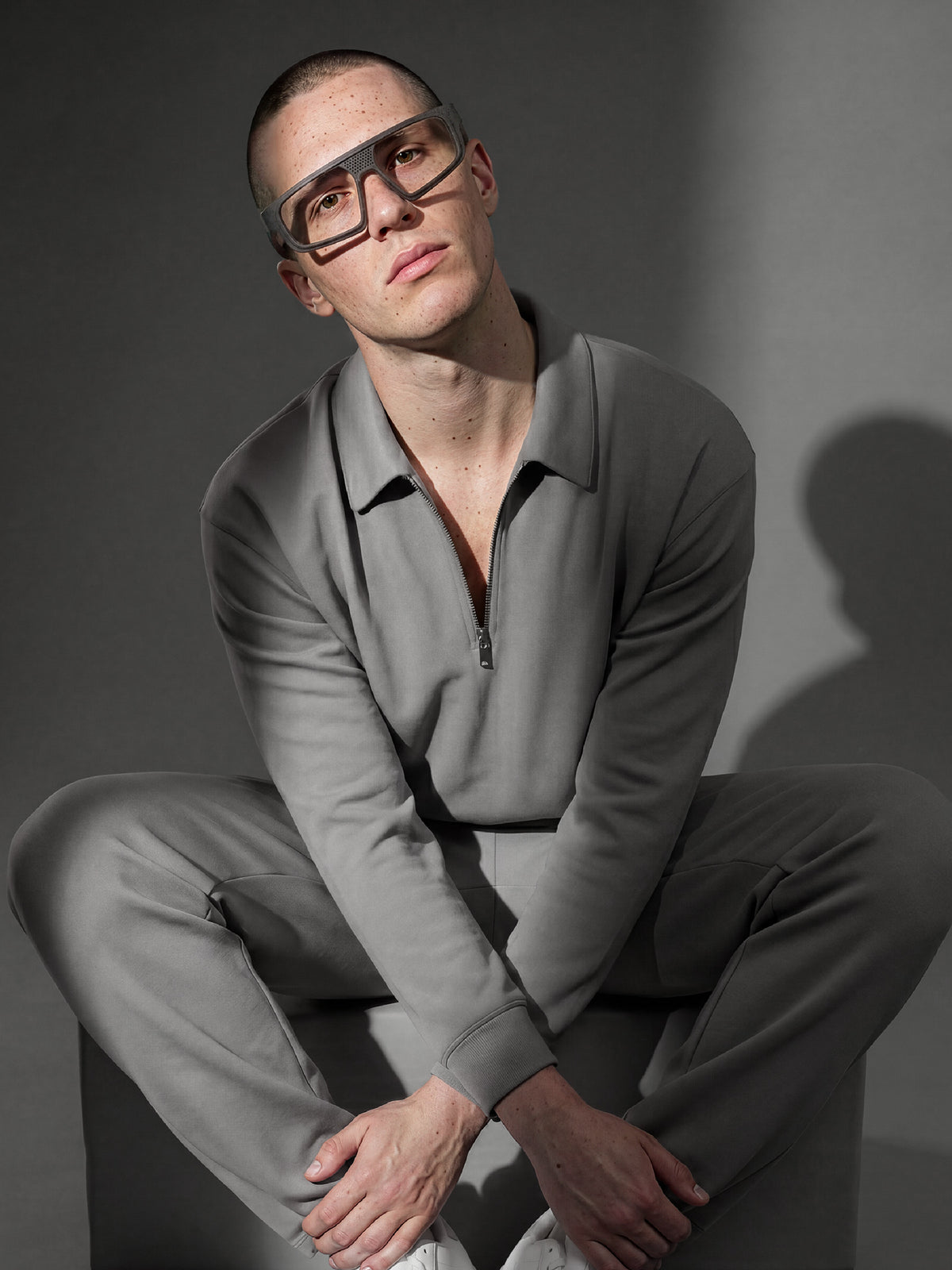 Editorial shot of a model in a sage zip polo wearing Blynq Kyro Black frames