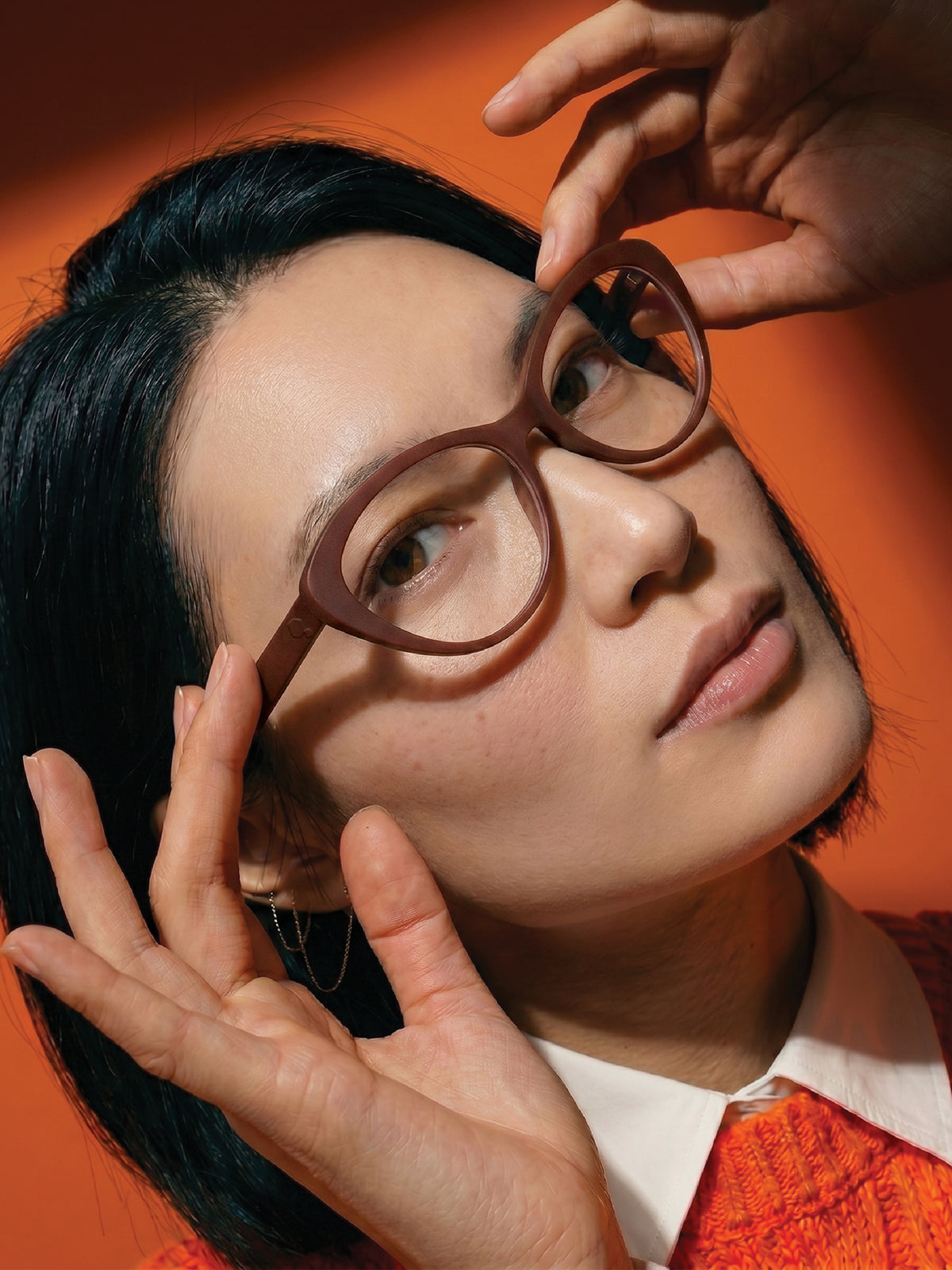 Close-up of Blynq Ora rounded glasses in Cordovan worn by a model
