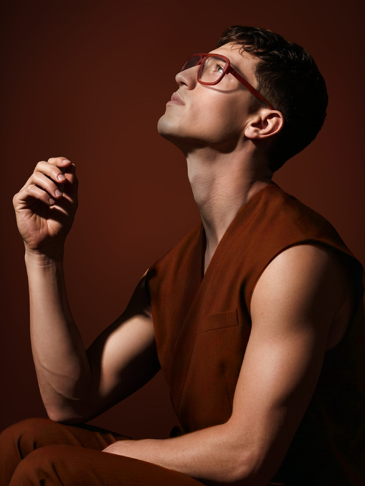 Editorial shot of a model in a rust sleeveless outfit wearing Blynq Vort Cordovan frames