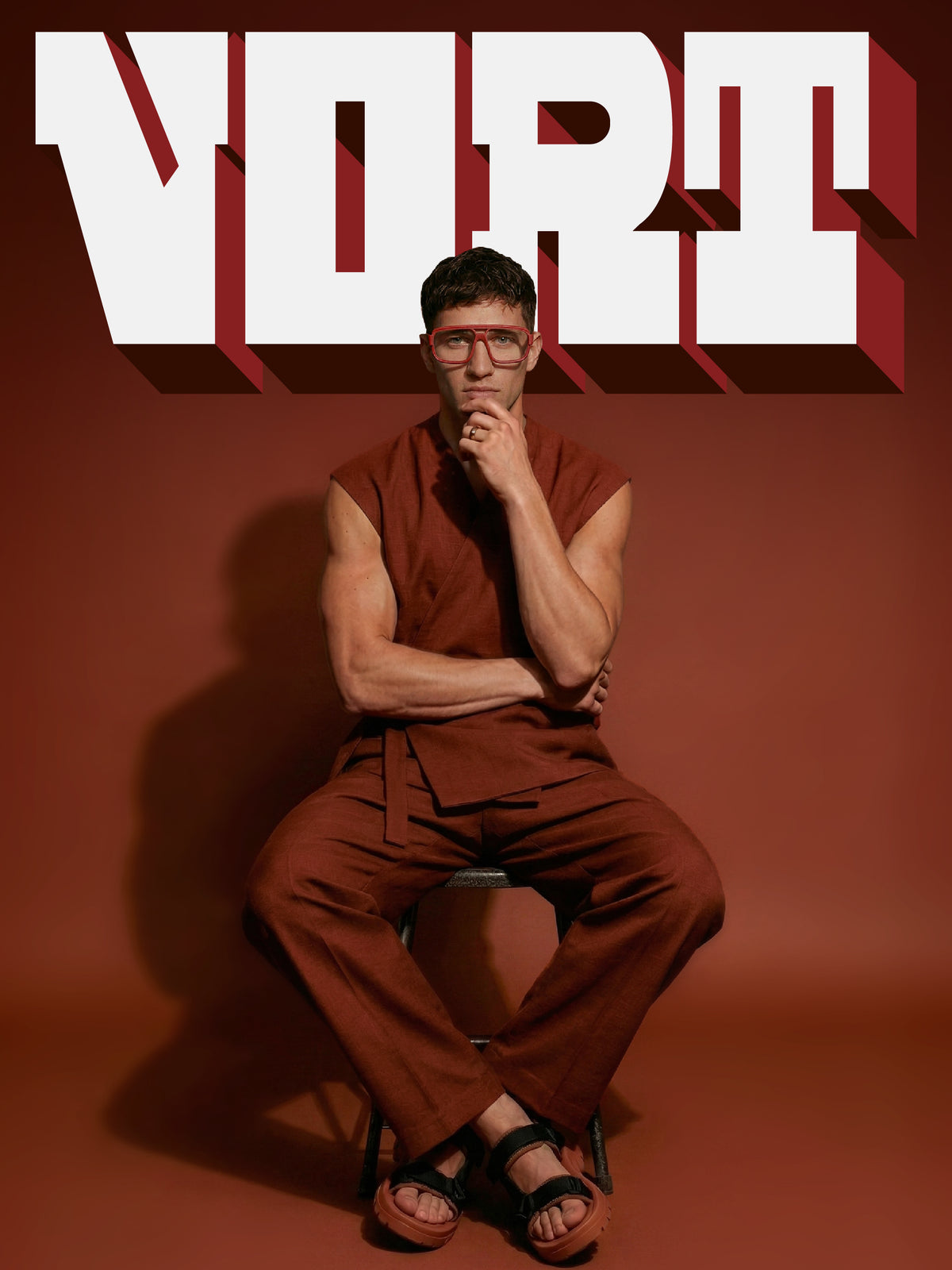 Vort campaign cover: model in a rust sleeveless outfit wearing Blynq Vort double-bridge navigator glasses in Cordovan Main image
